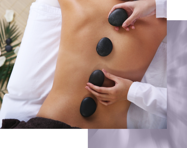 Massage therapist placing hot stones on person's back